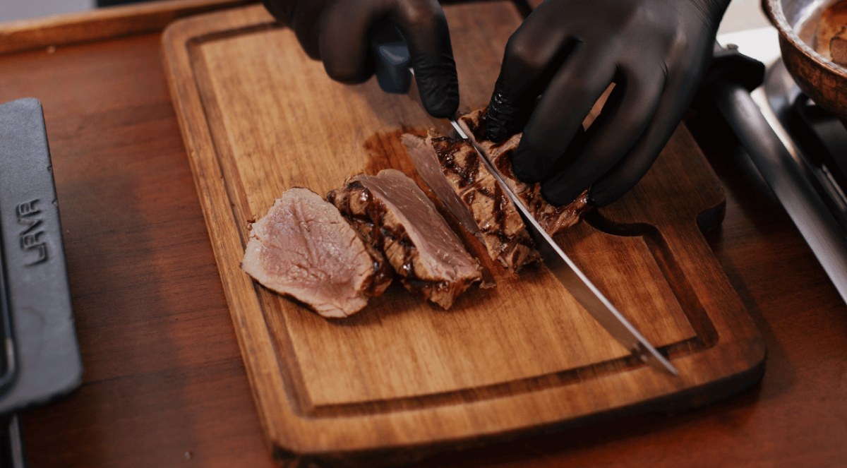 Nuz Restaurant - chef slicing dry-aged beef on a wooden board